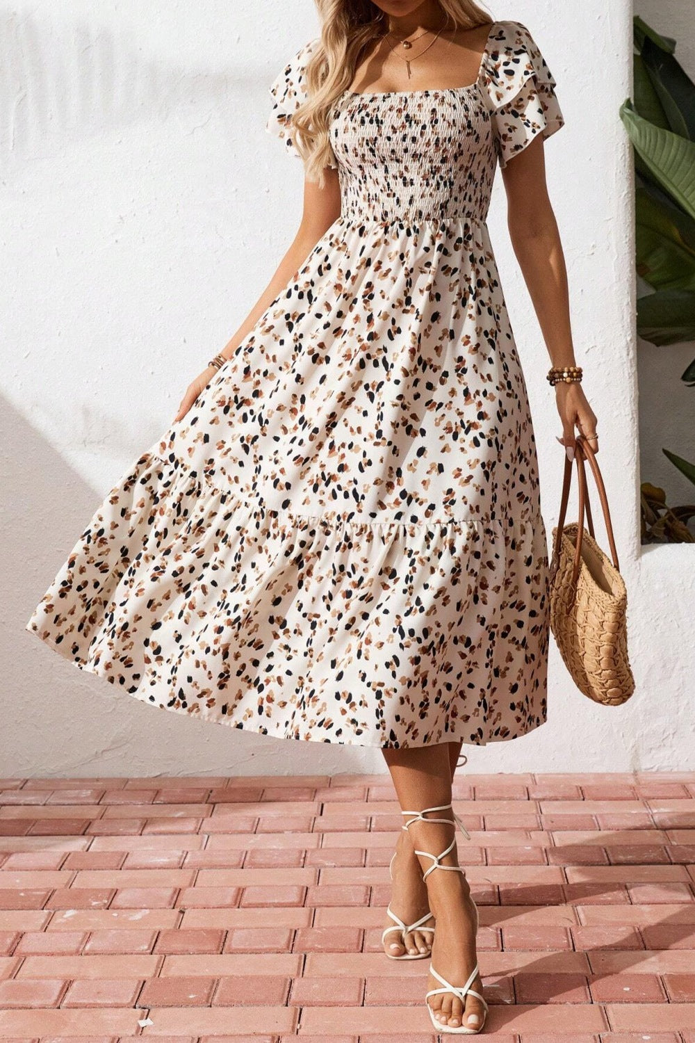 Woman wearing a floral dress standing on a brick patio.