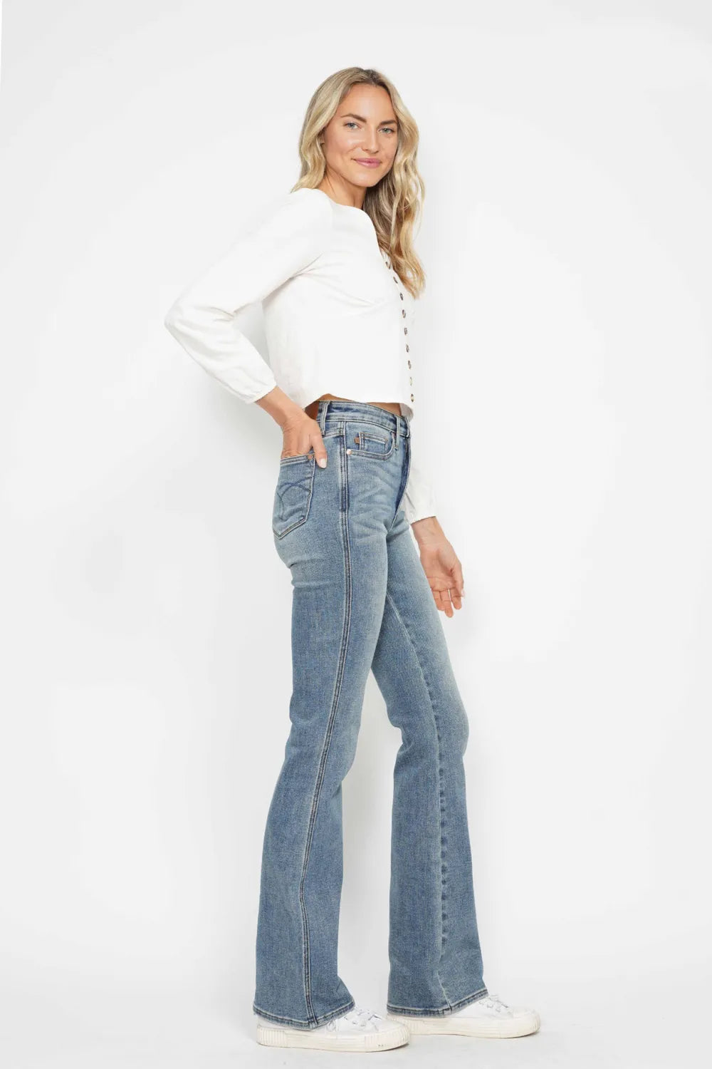 Woman wearing a white top and blue jeans on a white background