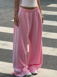 Person wearing pink track pants with white stripes on a street
