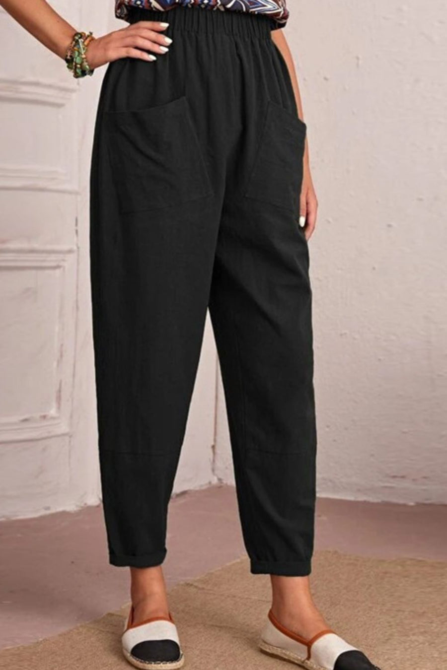 Person wearing black pants with a plain background