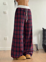 Person wearing red plaid pajama pants with a white waistband indoors.