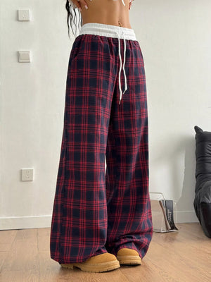 Person wearing red plaid pajama pants with a white waistband indoors.