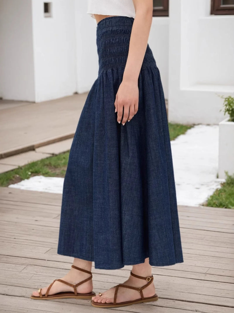 Person wearing a blue denim skirt on a wooden deck.
