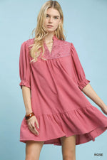 Woman wearing a pink dress with lace details on a light blue background