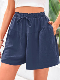 Navy blue shorts with a drawstring waist worn by a person.