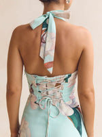 Woman wearing a floral dress with a neck scarf on a plain background