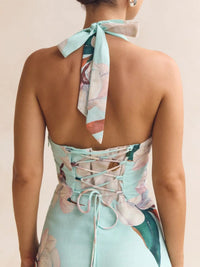 Woman wearing a floral dress with a neck scarf on a plain background