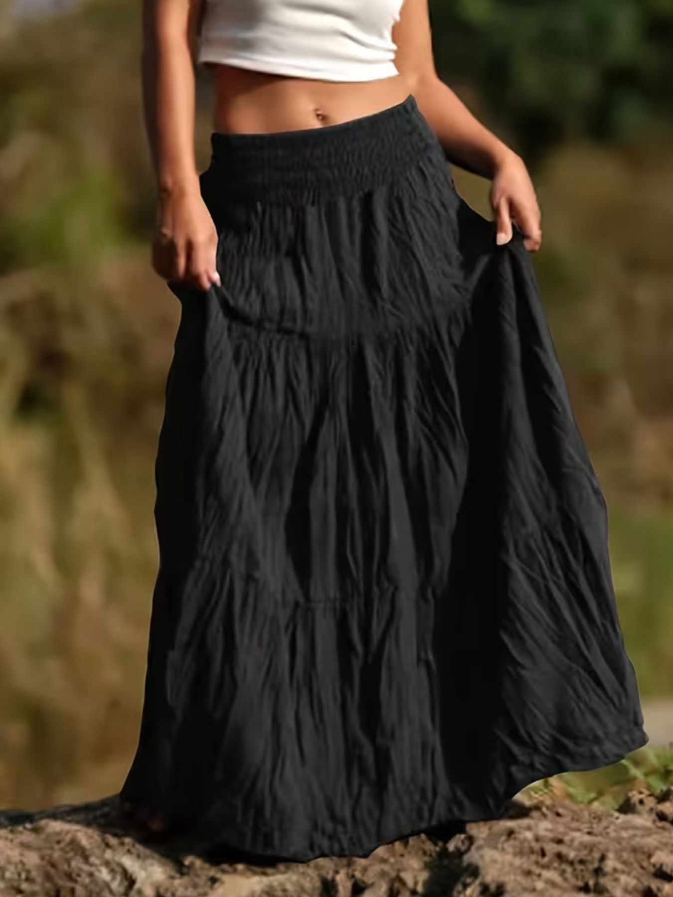 Person wearing a black tiered skirt with a blurred natural background