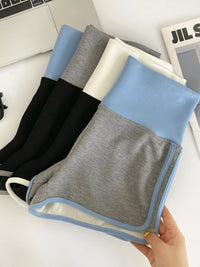 Set of folded towels in black, gray, and blue held by a hand on a white surface.