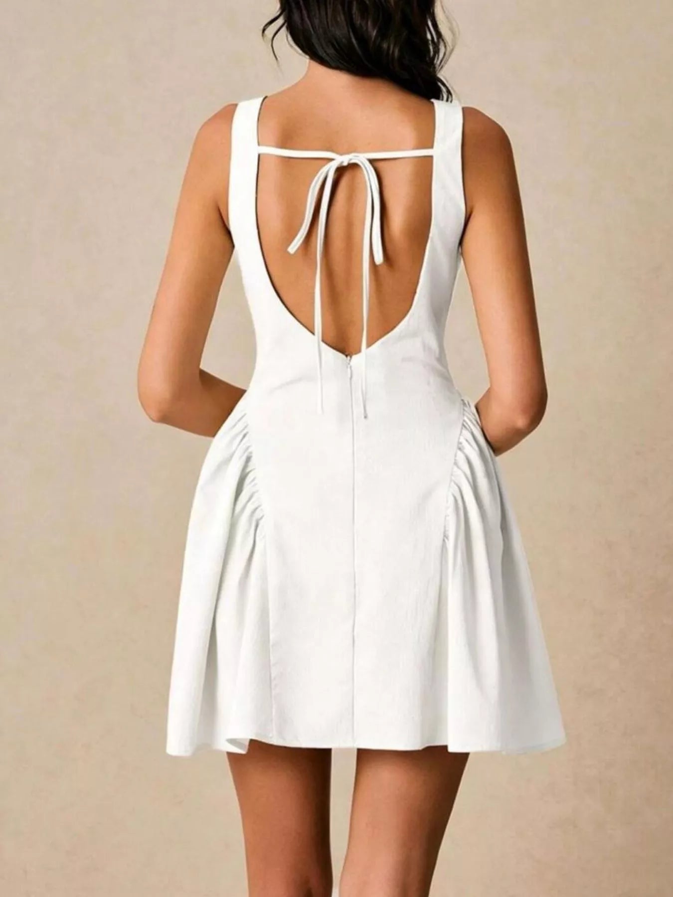 White dress with open back on a plain background