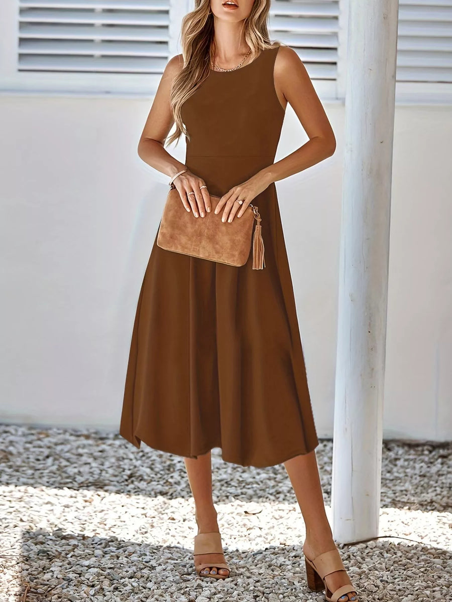 Woman wearing a brown dress holding a matching handbag against a white background