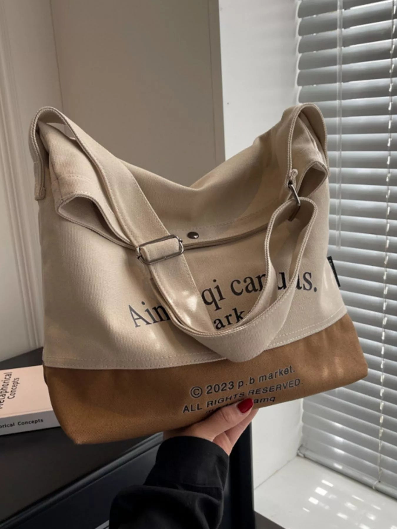 Beige tote bag with text held by a person indoors.