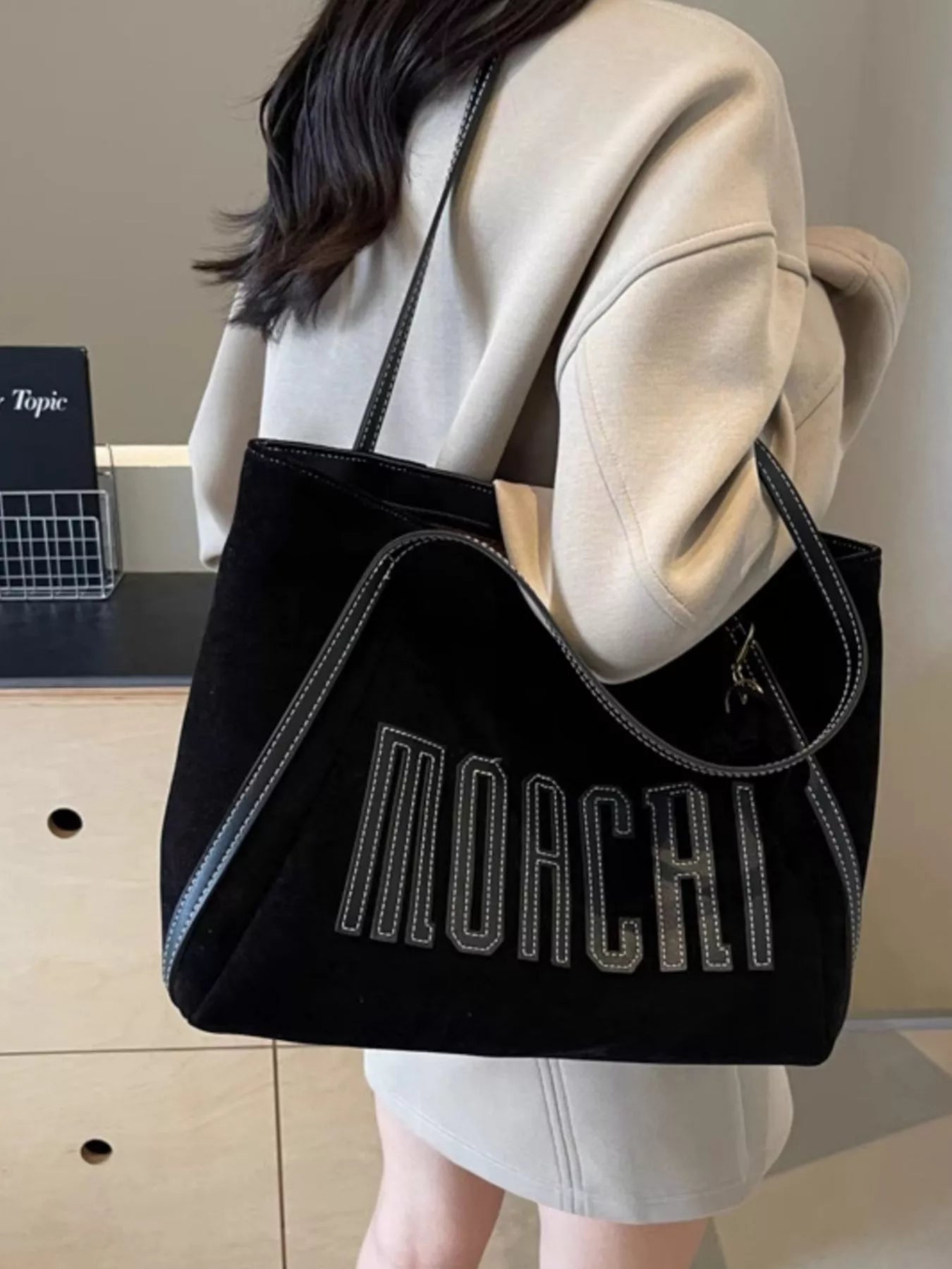 Person holding a black tote bag with 'Mocchi' branding.