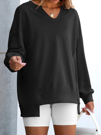 Person wearing a black oversized sweatshirt and white shorts against a neutral background