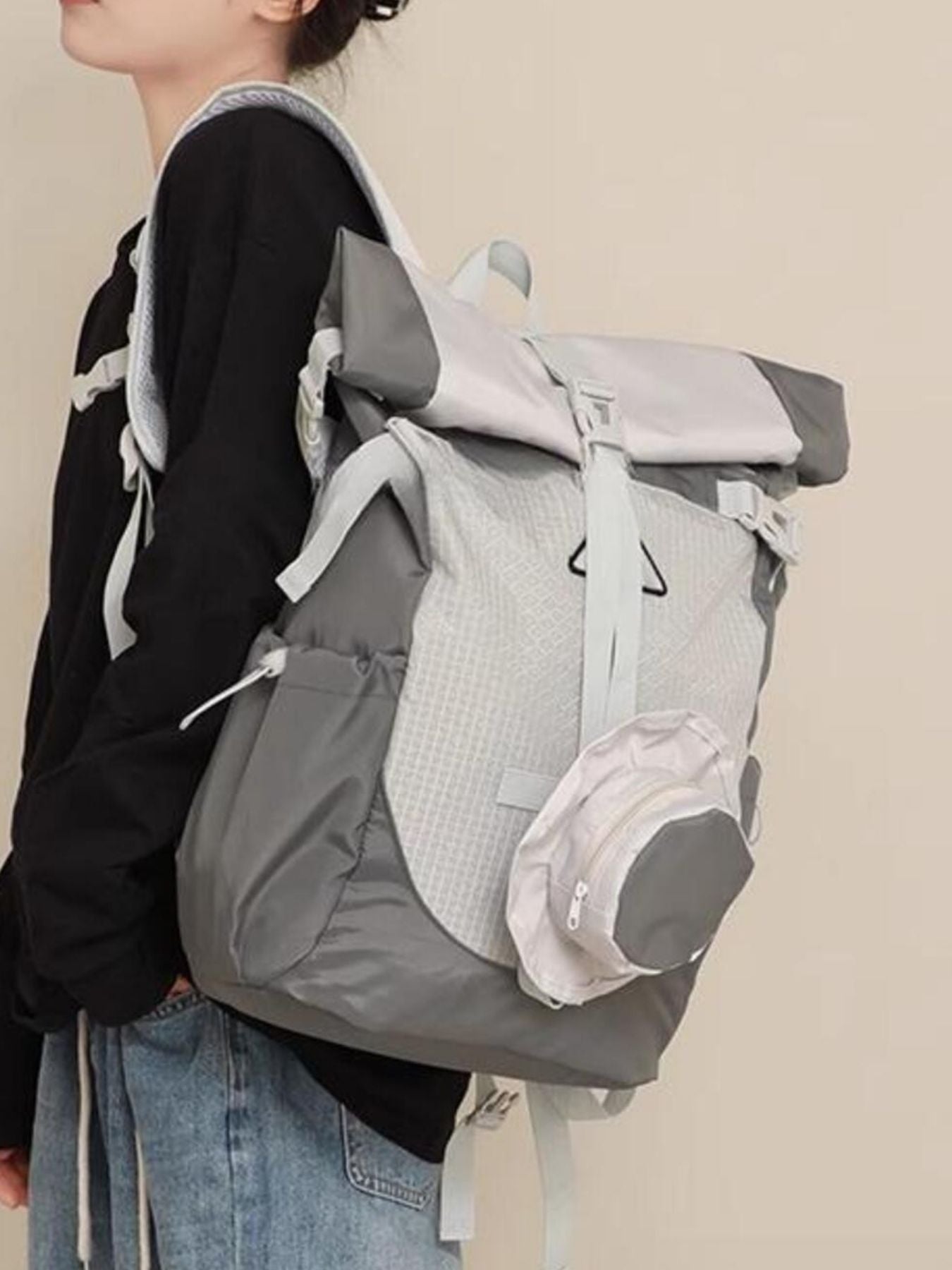 Person wearing a large gray backpack with a beige background
