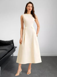Woman wearing a beige sleeveless dress in a minimalistic room with a black sofa.