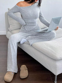 Person wearing a gray outfit sitting on a couch with a laptop.