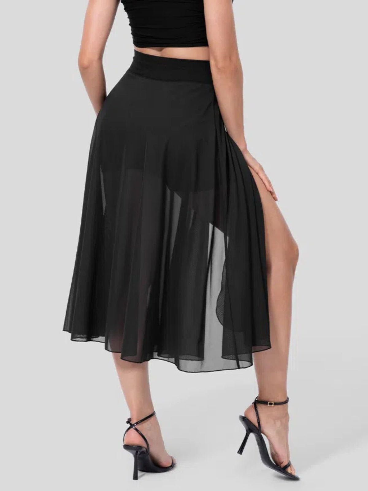 Black skirt with a high slit worn by a model on a gray background