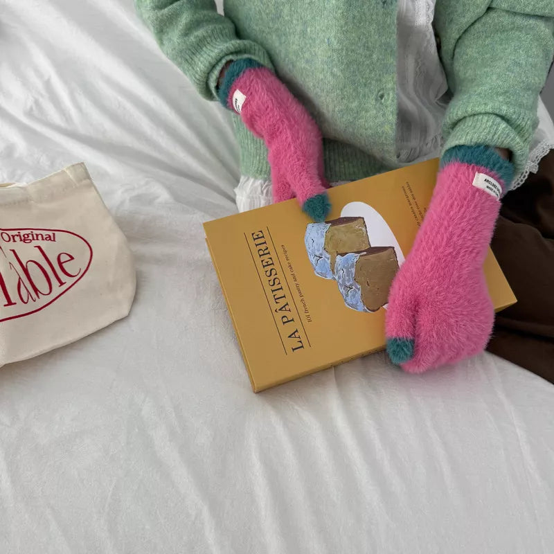 Person wearing pink gloves holding a book titled 'La Patisserie' on a bed.