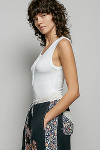 Woman wearing a white tank top and floral apron against a plain background