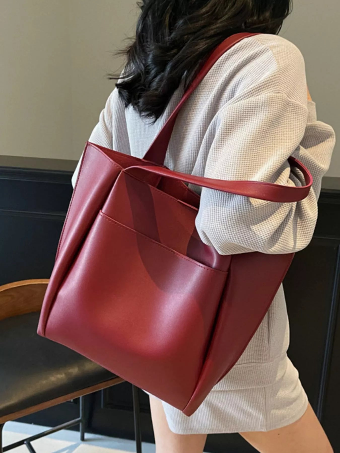 Person holding a red tote bag indoors