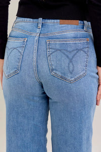 Blue jeans with a brand logo on the back pocket against a neutral background