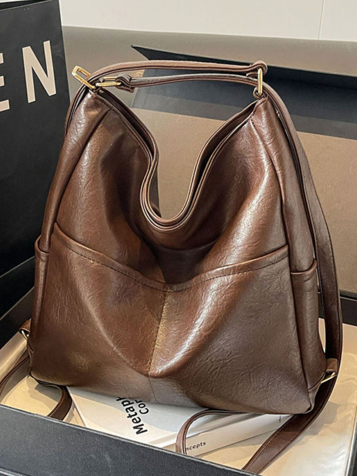 Brown leather handbag on a reflective surface with a blurred background