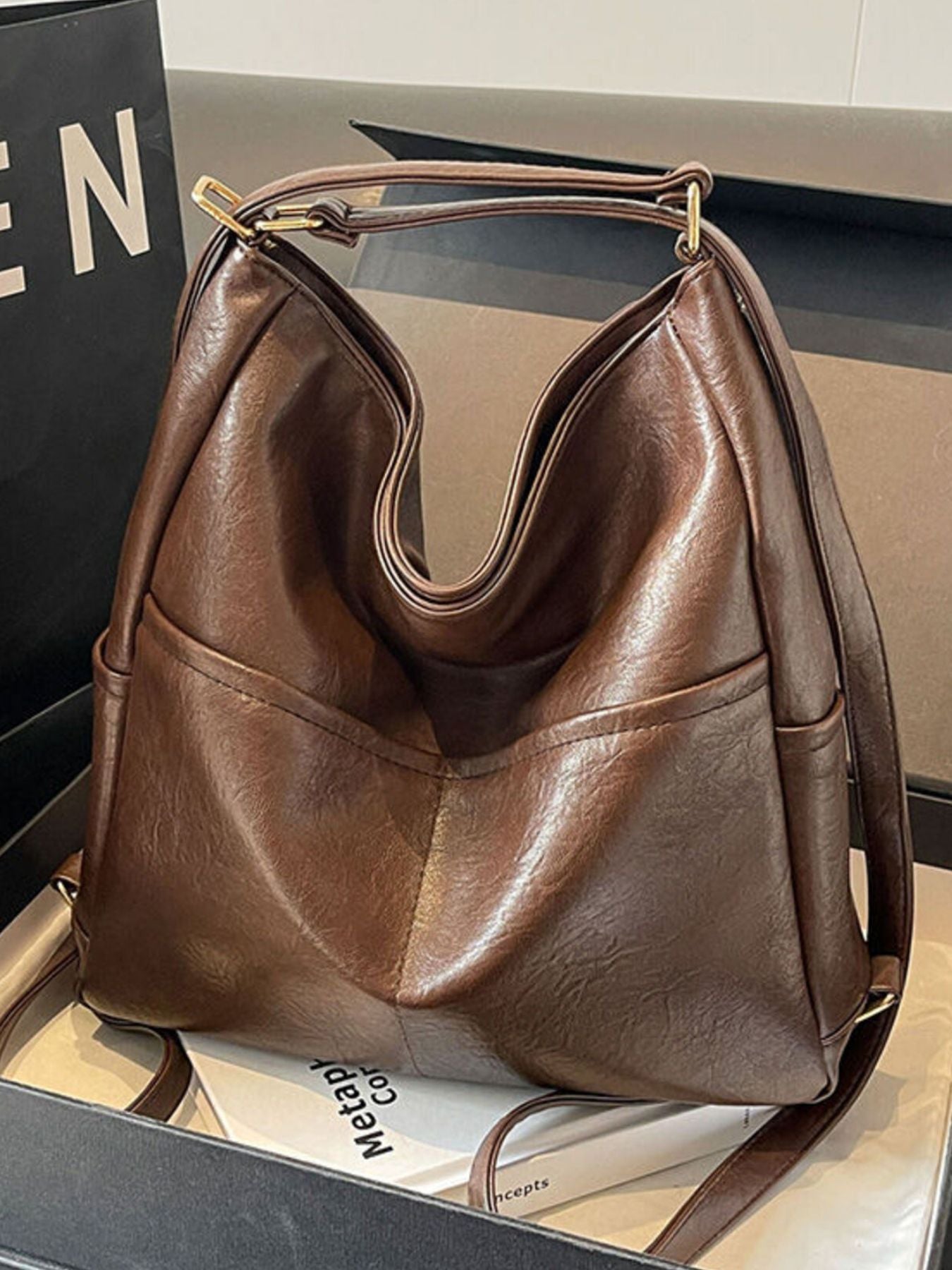 Brown leather handbag on a reflective surface with a blurred background