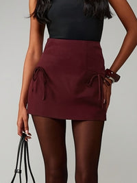 Person wearing a burgundy skirt with a plain background