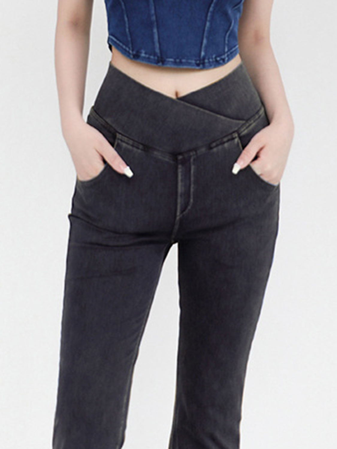 Person wearing black high-waisted jeans with a white background