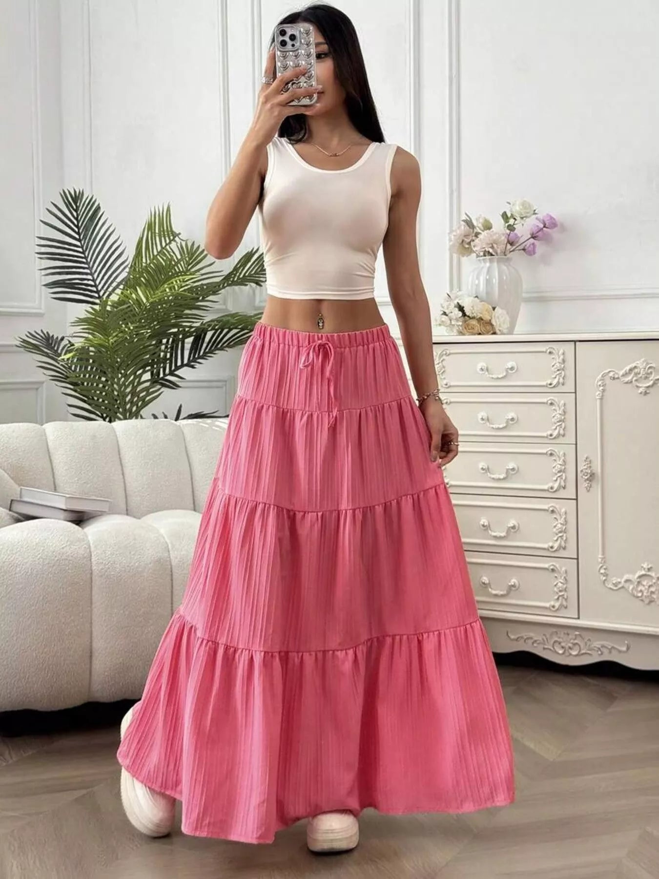 Woman wearing a pink tiered skirt and white top in a living room setting.