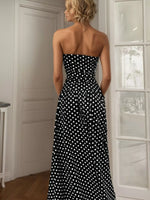 Woman wearing a black strapless dress with white polka dots in a room.