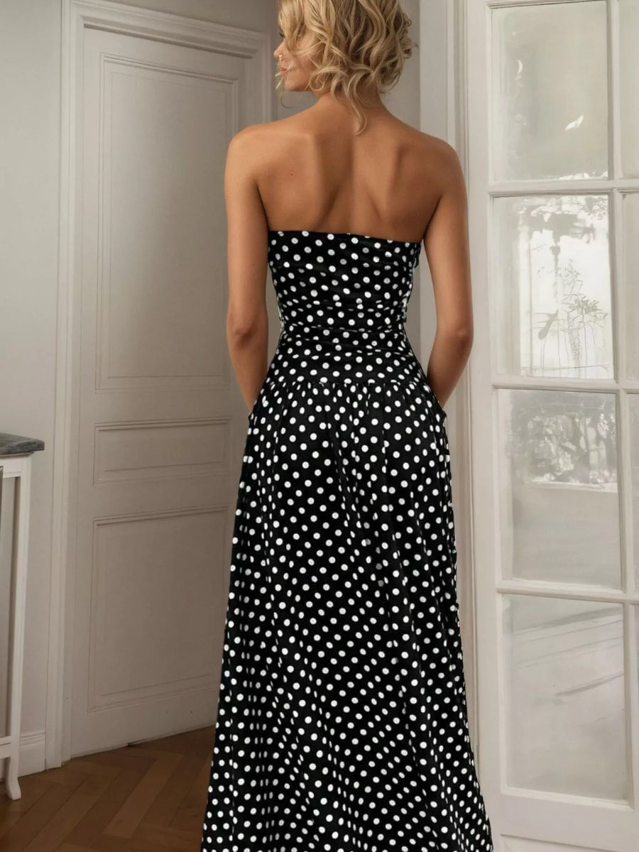 Woman wearing a black strapless dress with white polka dots in a room.