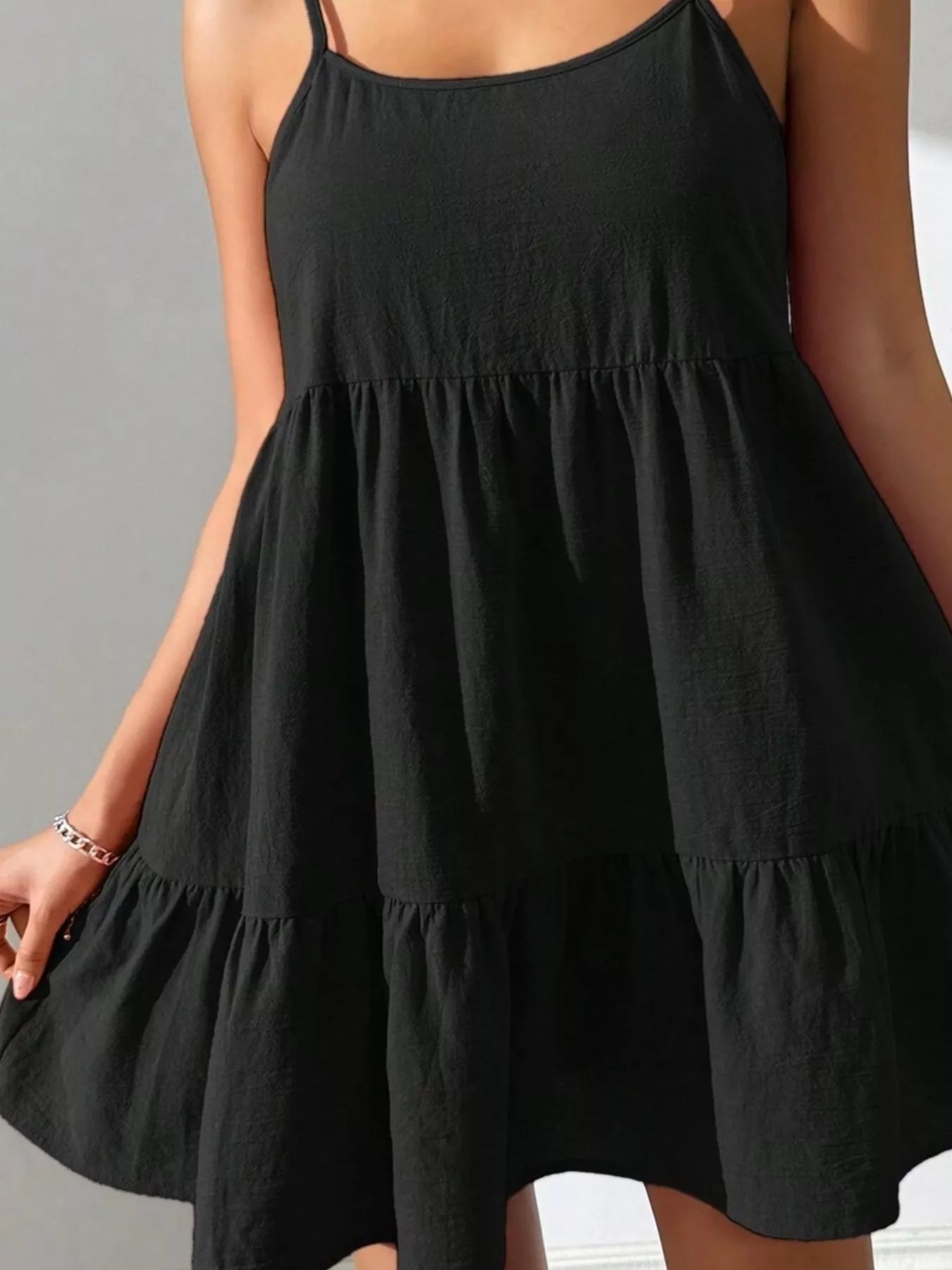 Black tiered dress worn by a person against a neutral background