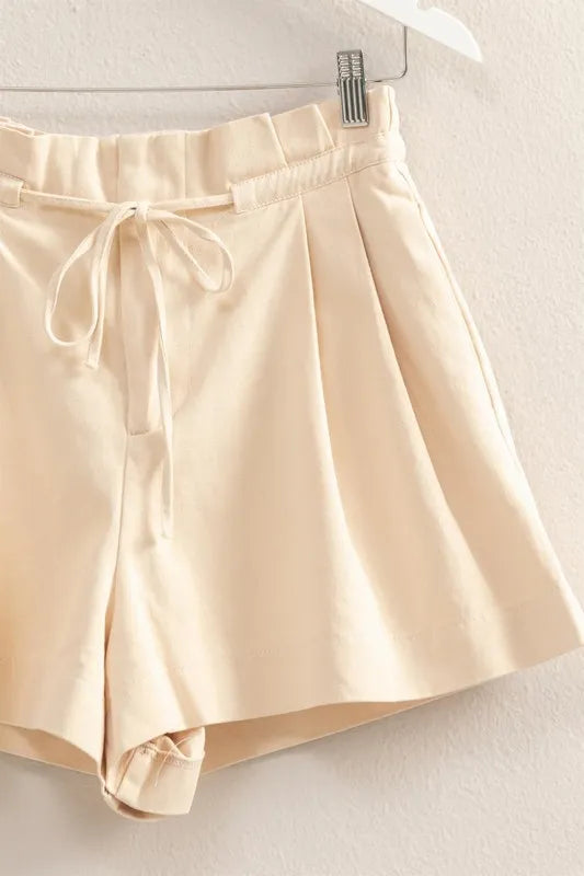 Beige shorts on a hanger against a neutral background