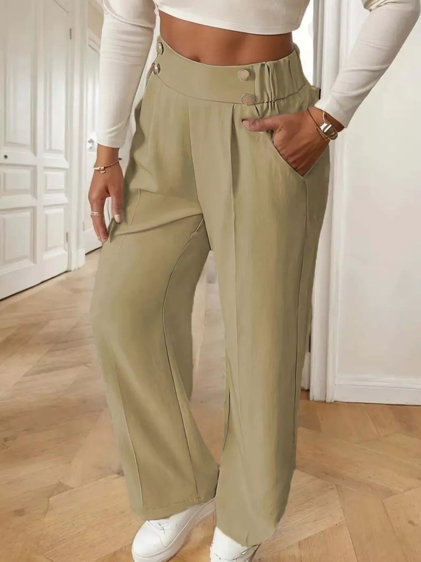 Person wearing beige wide-leg pants and a white top indoors.