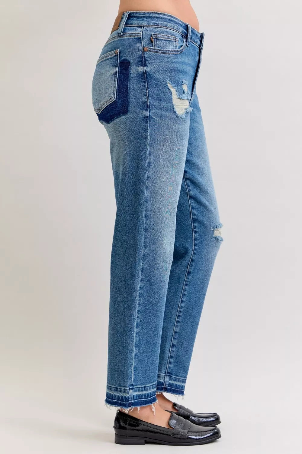 Blue jeans with distressed details on a plain background