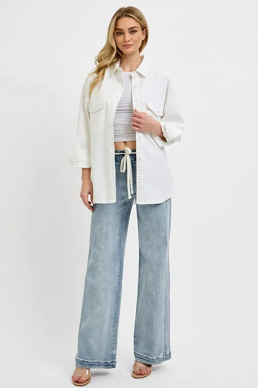 Woman wearing a white jacket, white top, and blue jeans on a white background