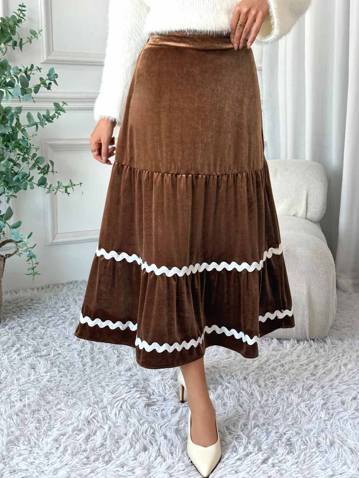 Brown tiered skirt with white trim worn by a person in a home setting.