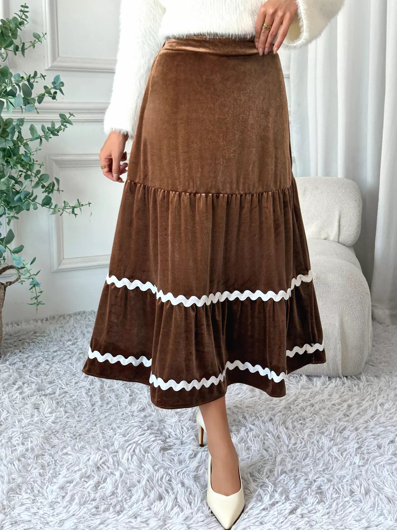 Brown tiered skirt with white trim worn by a person in a home setting.