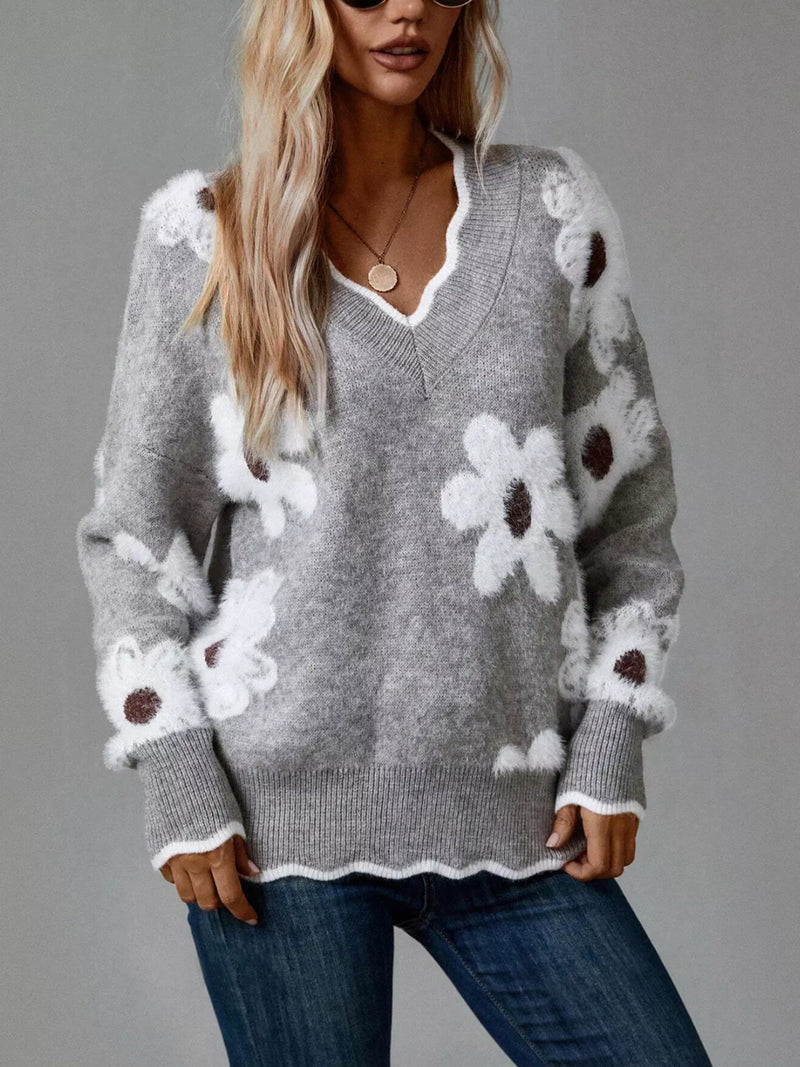 Woman wearing a gray sweater with white floral patterns on a gray background