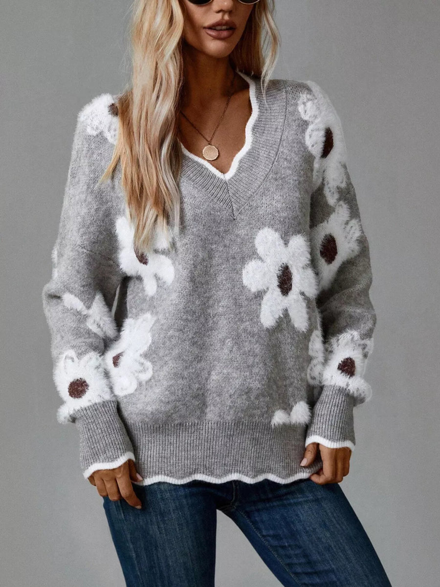 Woman wearing a gray sweater with white floral patterns on a gray background