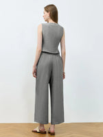 Woman wearing a gray sleeveless top and wide-leg pants against a white background