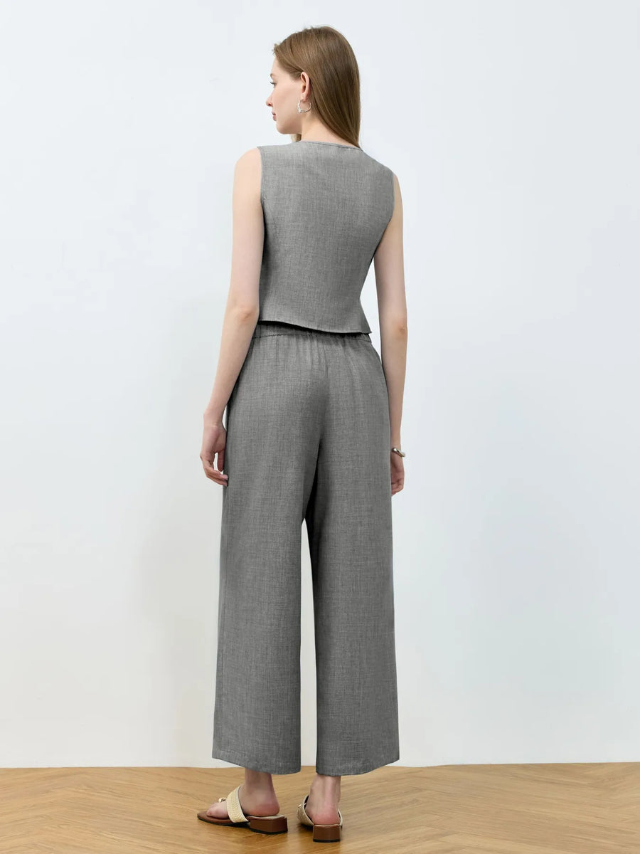 Woman wearing a gray sleeveless top and wide-leg pants against a white background