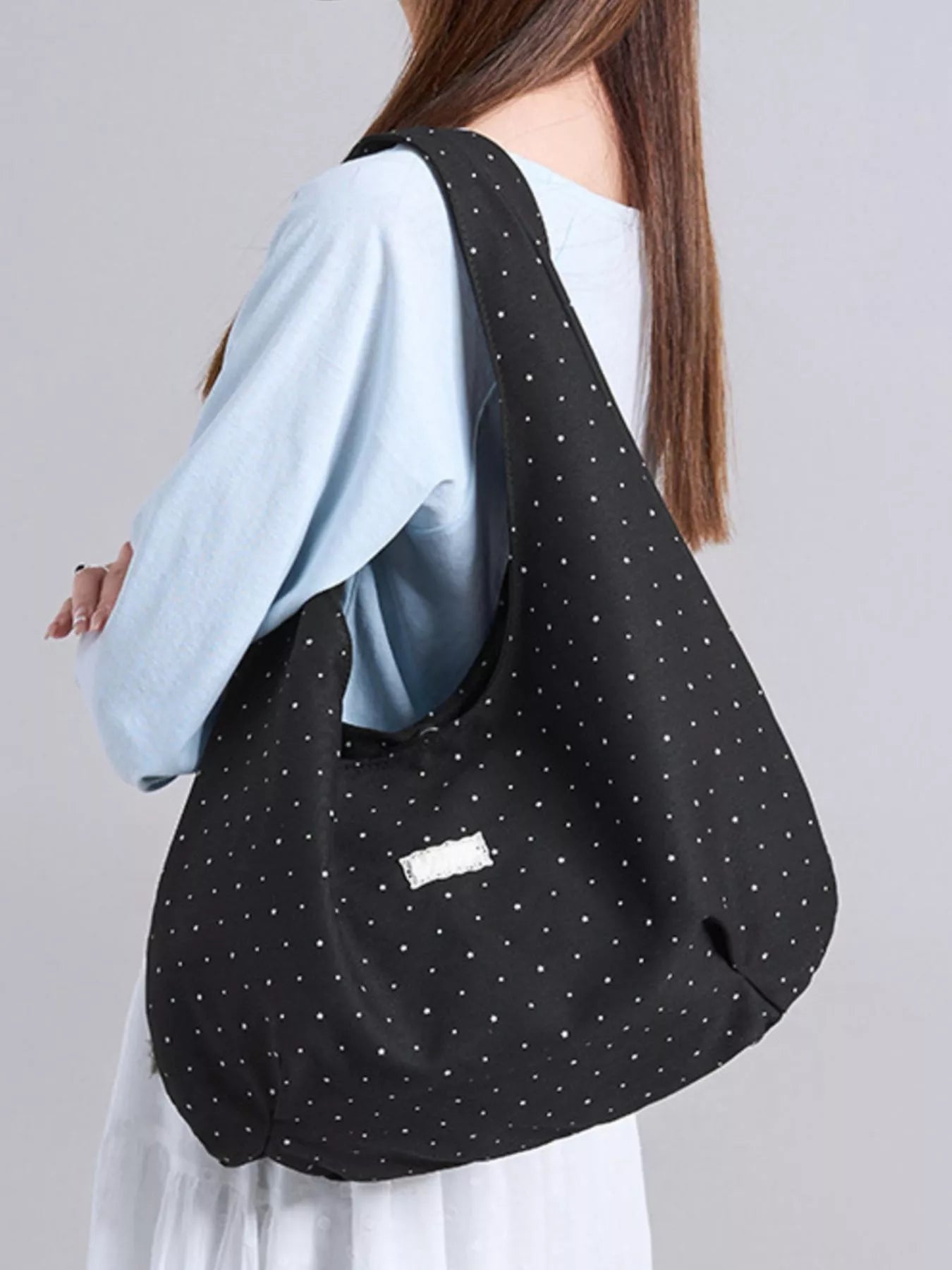 Person wearing a black polka dot bag on a plain background