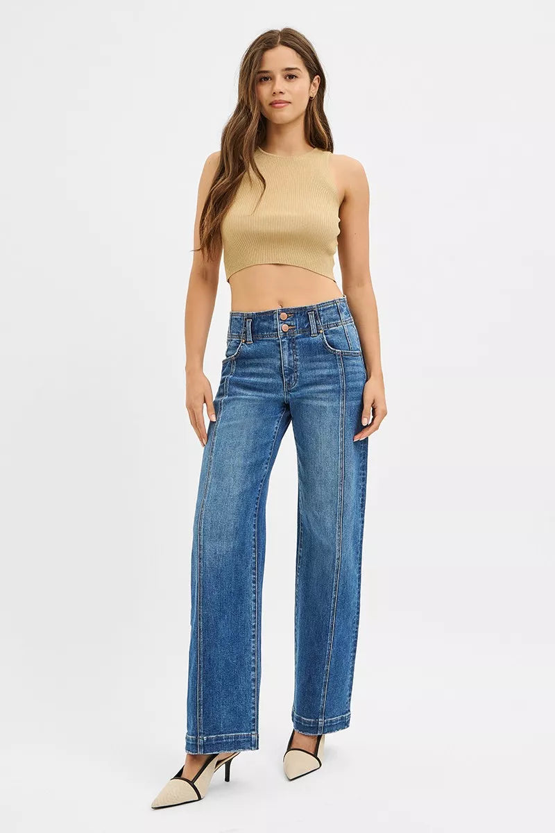 Woman wearing a beige top and blue jeans on a white background