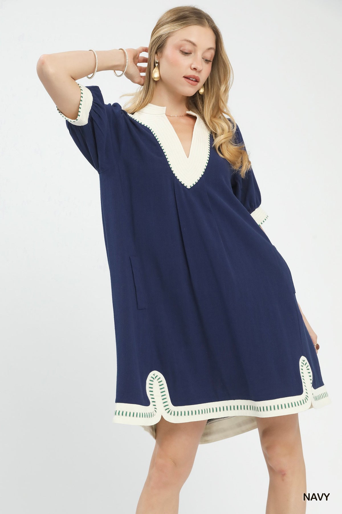 Woman wearing a navy dress with white trim on a white background