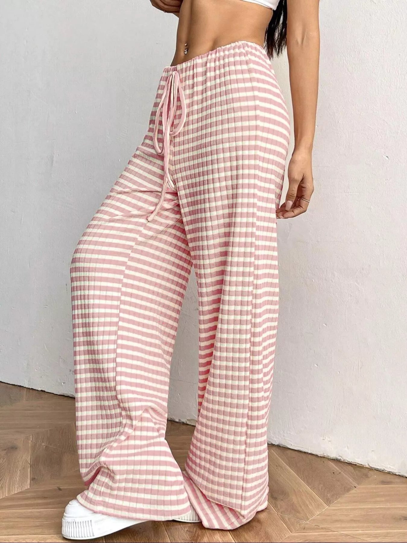 Person wearing pink and white checkered pants on a wooden floor.