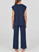 Woman wearing a navy blue outfit with a top and pleated pants on a white background