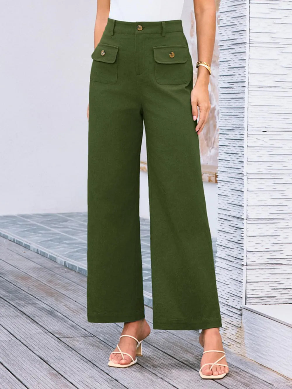 Green wide-leg pants worn by a person on a wooden deck.